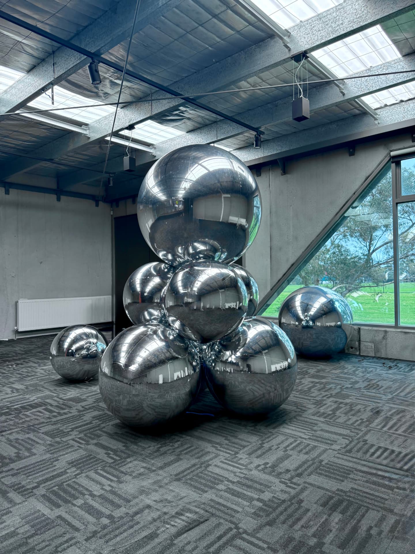 Large mirror sphere cluster installation by floor-to-ceiling windows